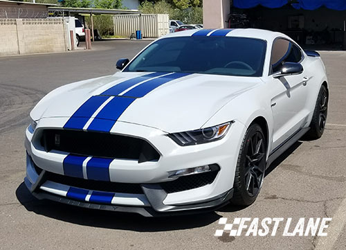 White Ford Mustang with dual blue vinyl stripes.